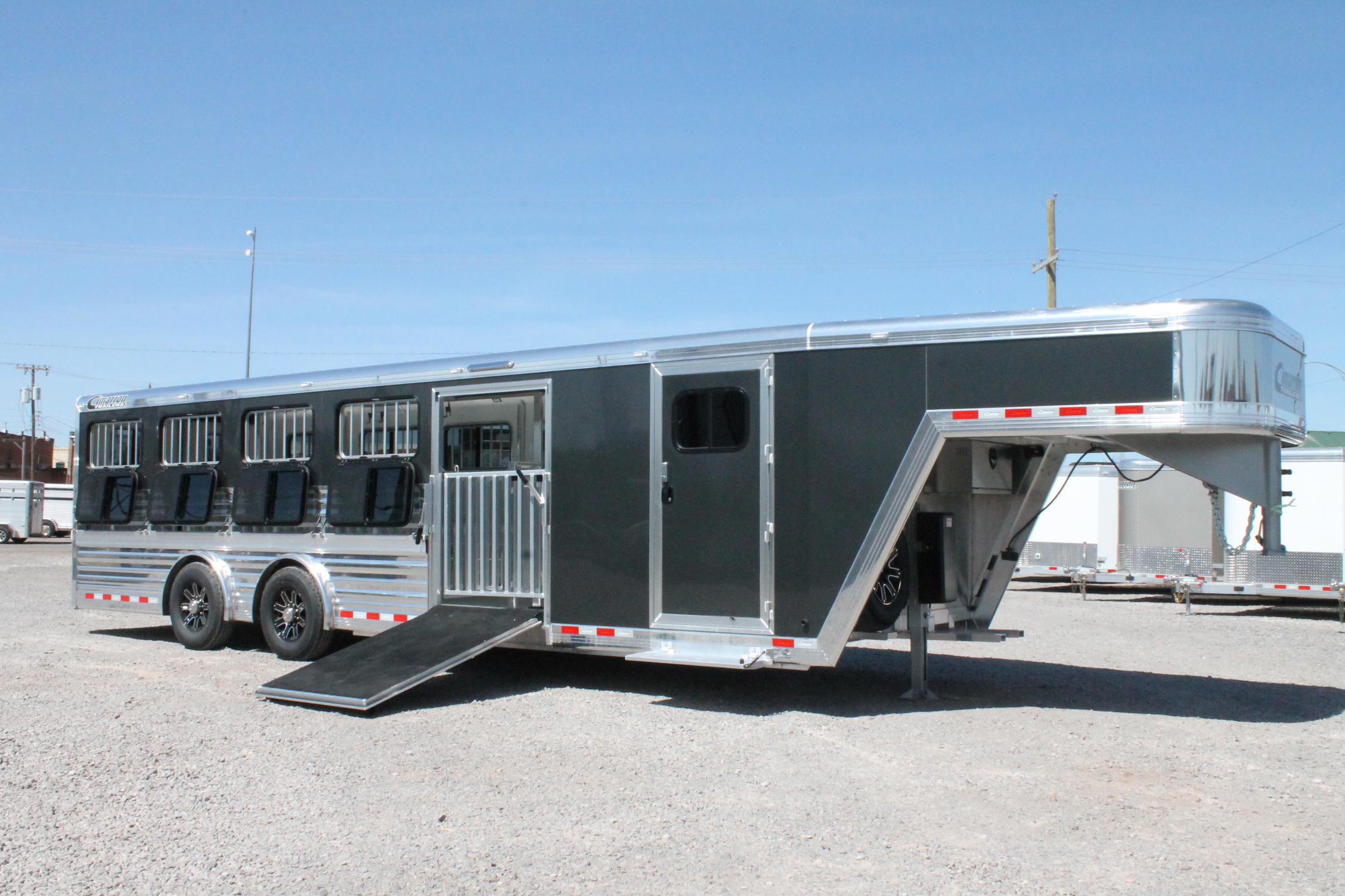 A Cimarron trailer parked in a gravel lot on a sunny day.