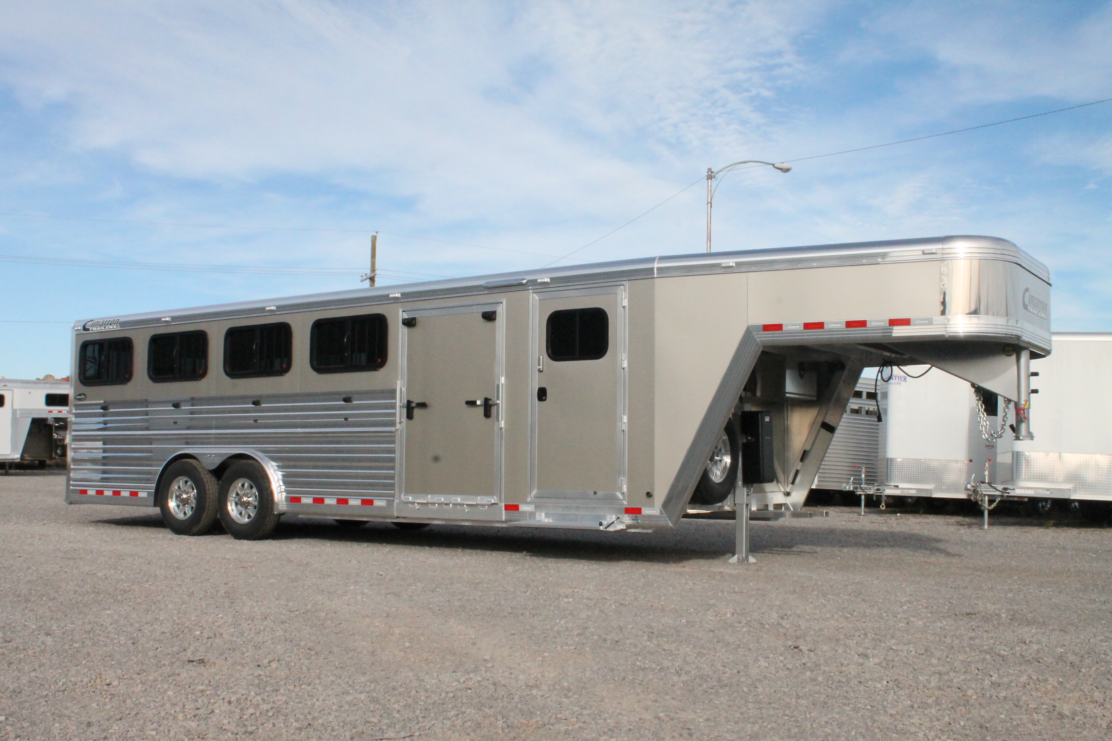 A Cimarron trailer that's parked in a gravel lot with other trailers